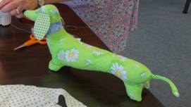 Stuffed animal, dachshund made out of green material with daisies on it.