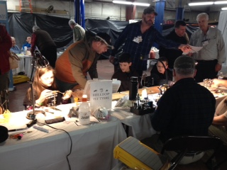 Children and adults at a table tying flies.