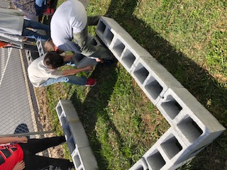 Three students using concrete blocks to build a raised bed. 