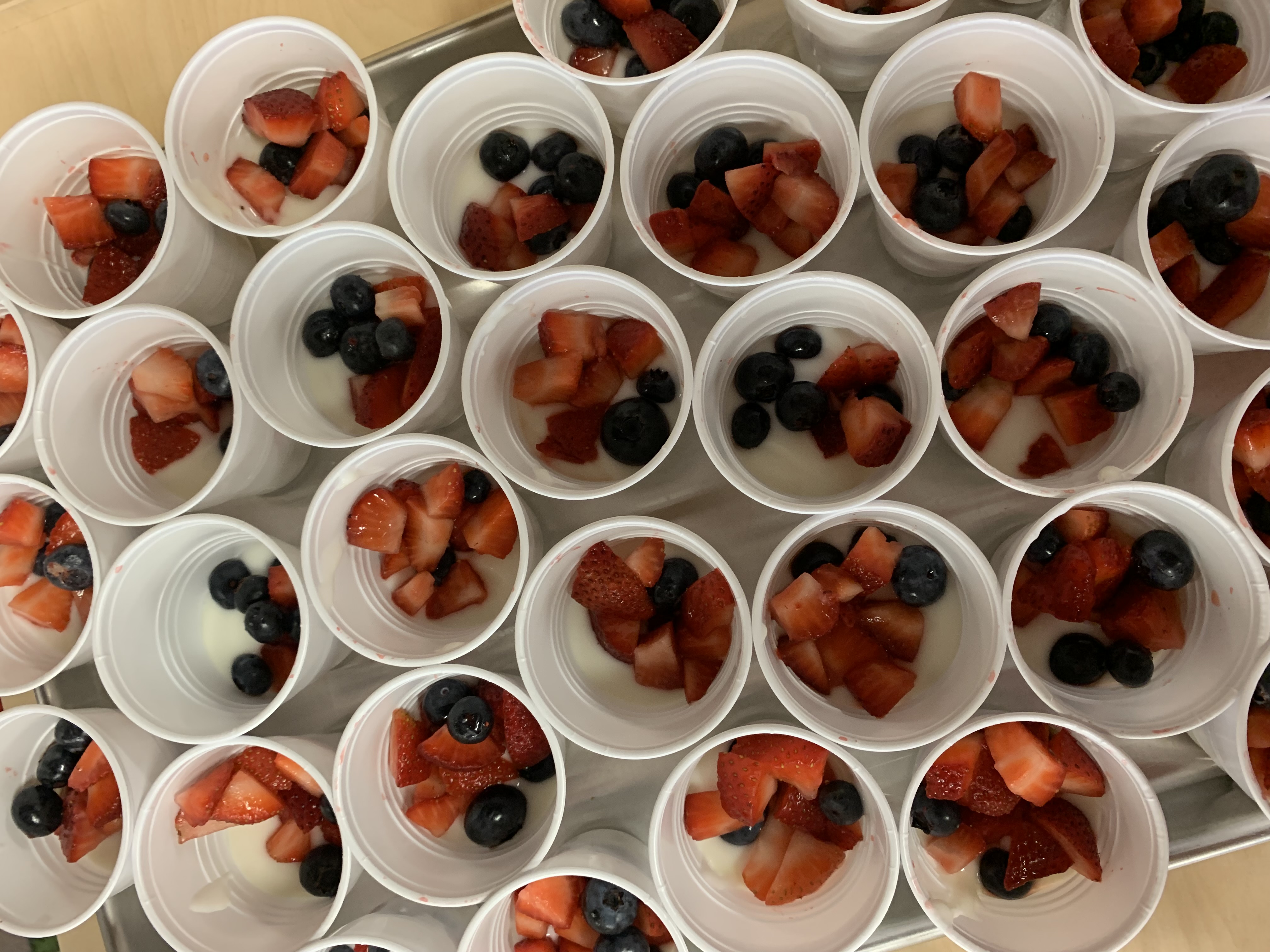 A tray of yogurt parfaits made with strawberries and blueberries.