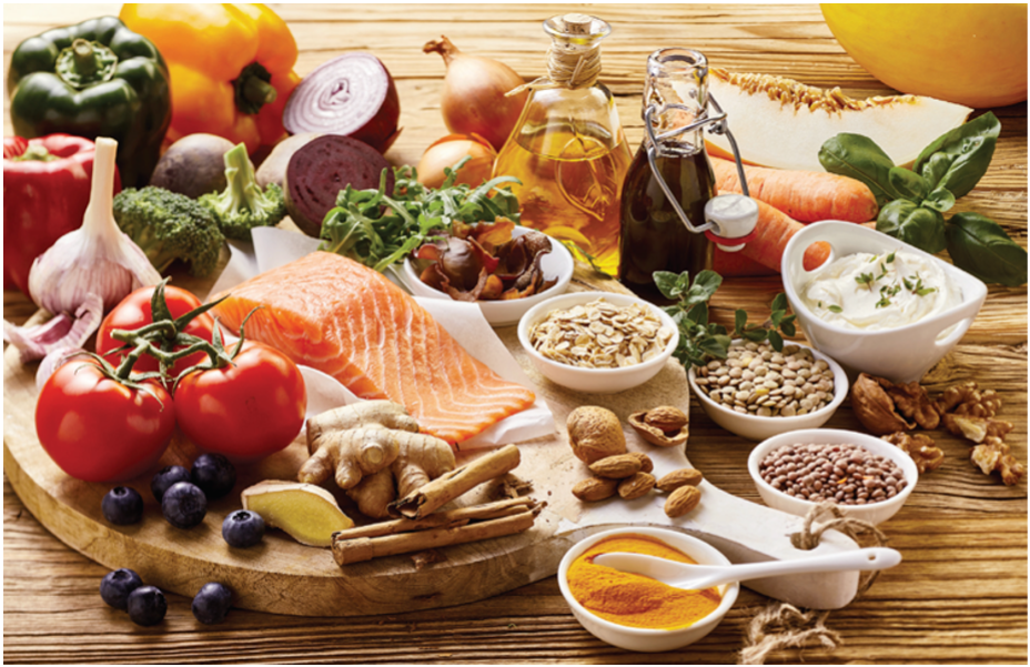 A table topped with an assortment of mediterranean ingredients including fish, garlic, tomato and olive oil.