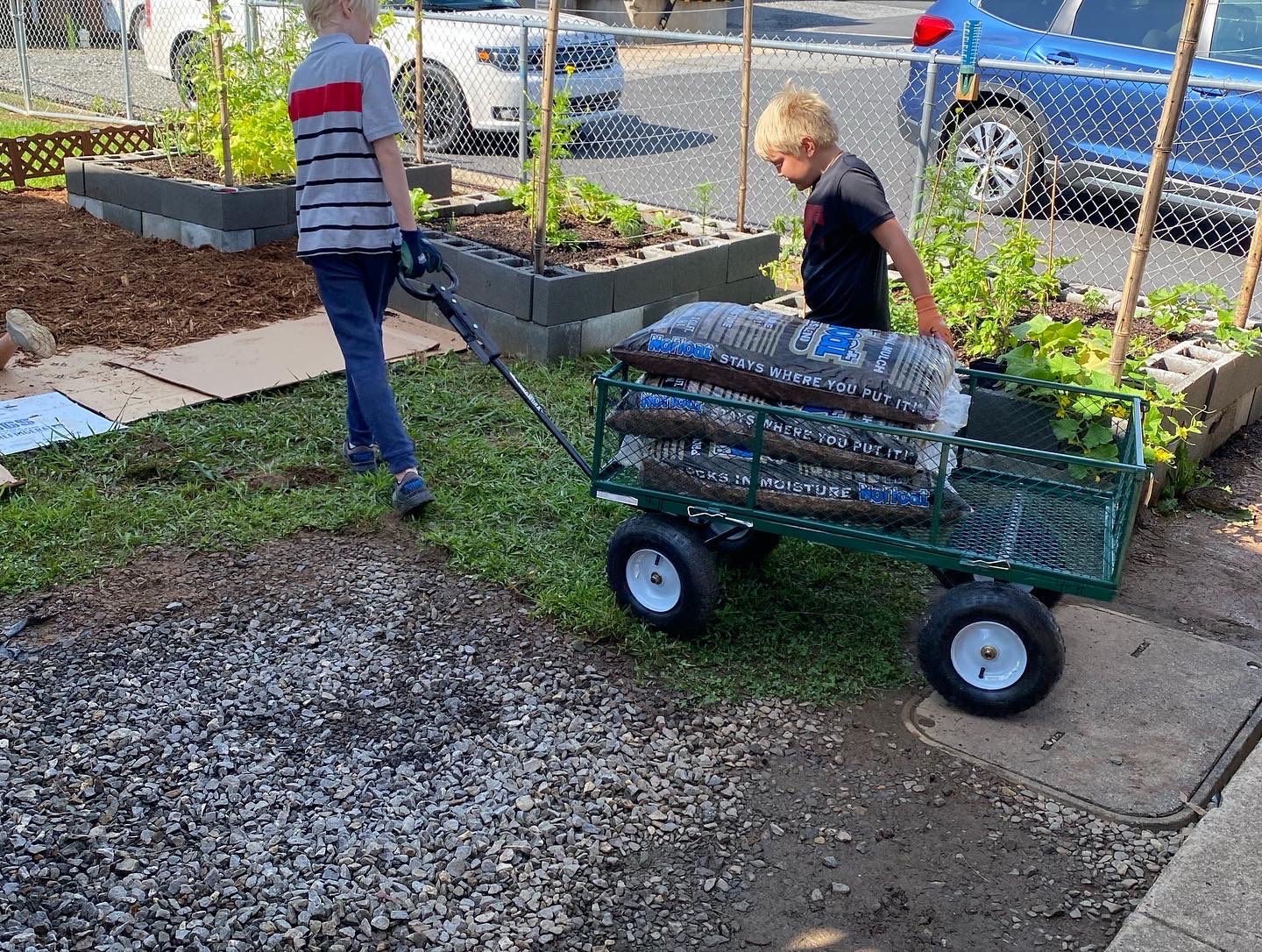 Children pull a wagon containing bags of mulch.