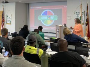 A classroom of adults is playing a Spin-Off review game on their phones with their instructor.