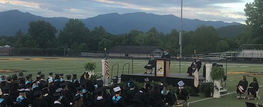 Graduates at a graduation ceremony outdoors.