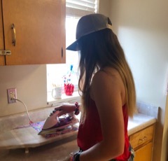 A girl with her back to the camera irons on a tabletop ironing board.