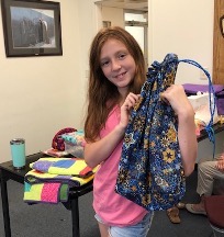 A girl holds up a handmade drawstring bag.