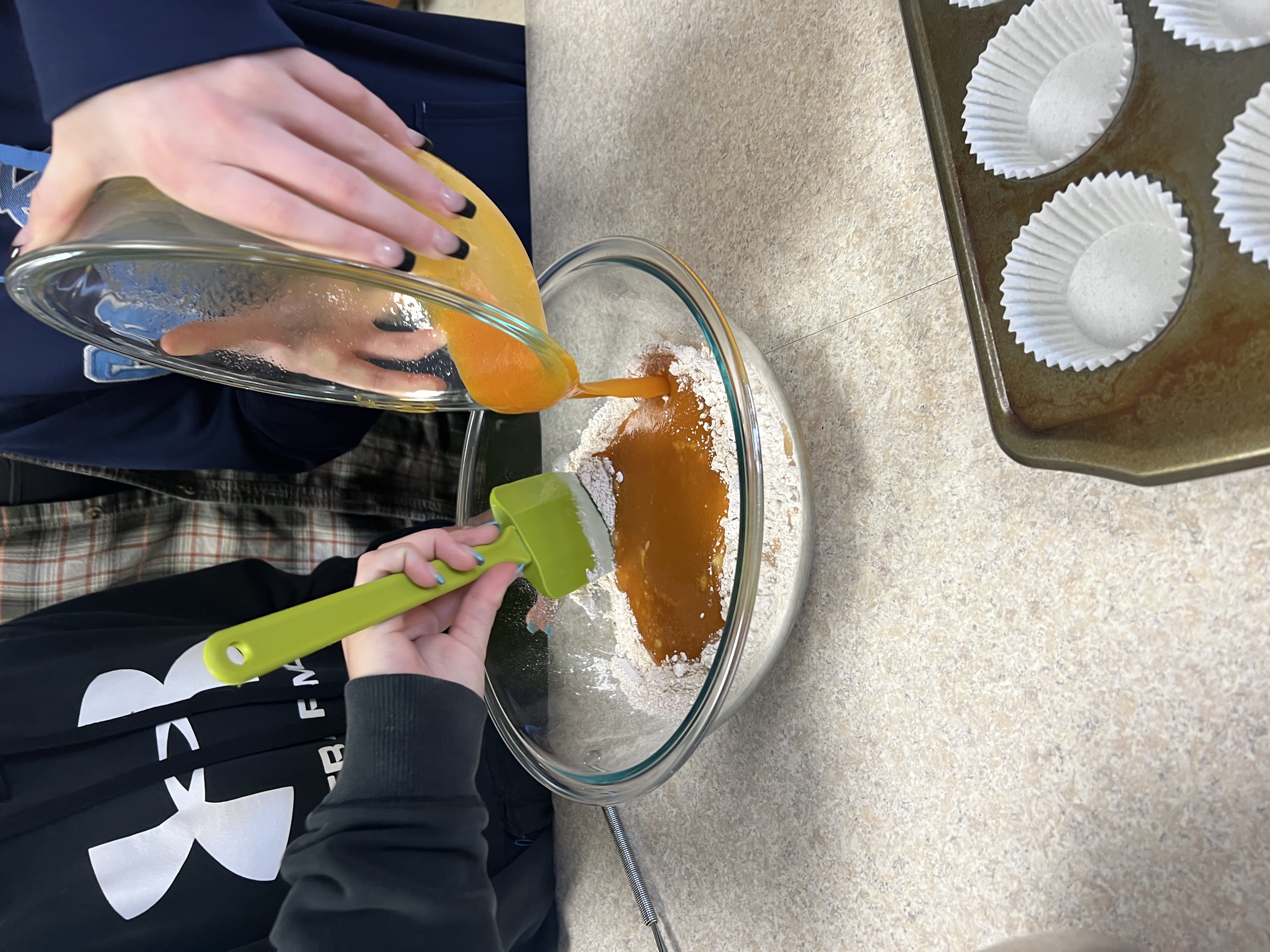 Students add a liquid pumpkin mixture to dry baking ingredients.
