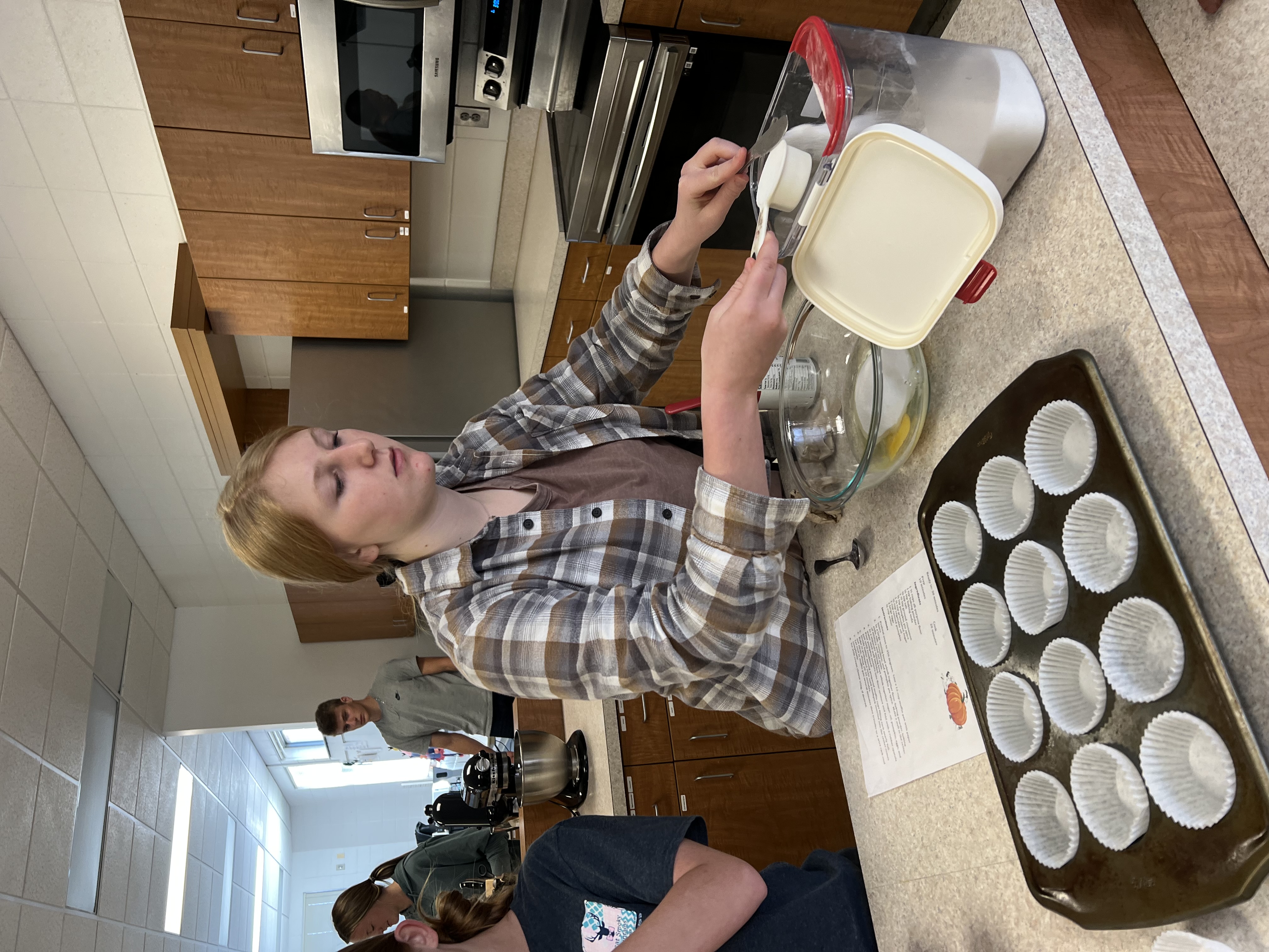 A student measures out dry ingredients from an air tight container.
