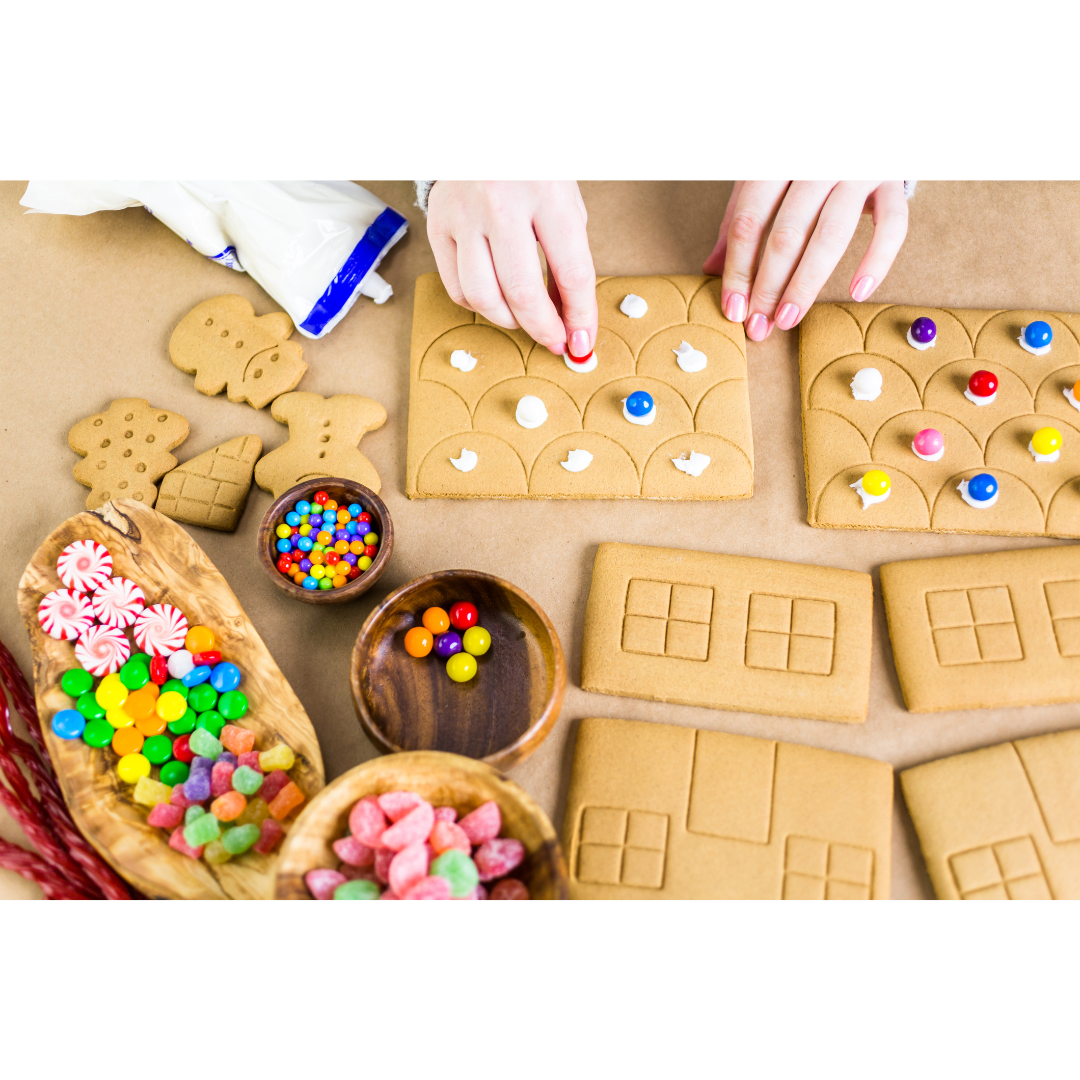 A person decorates the roof of an unfinished gingerbread house. 