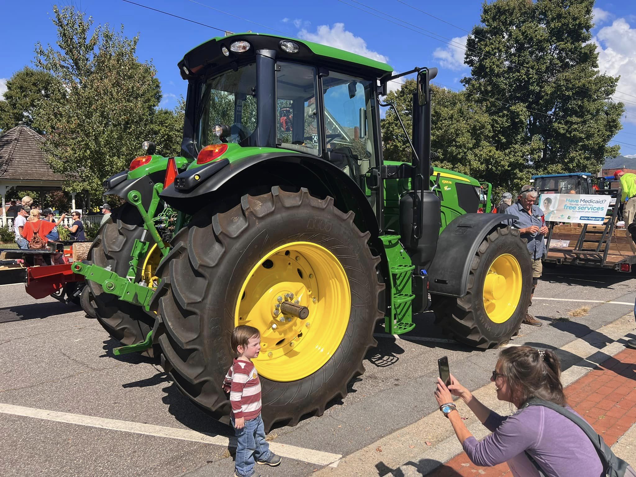 Child poses for picture by John Deere Tractor